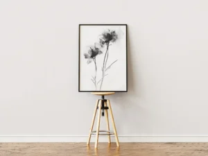 Minimalist black and white floral ink wash wall art framed on a wooden stool.