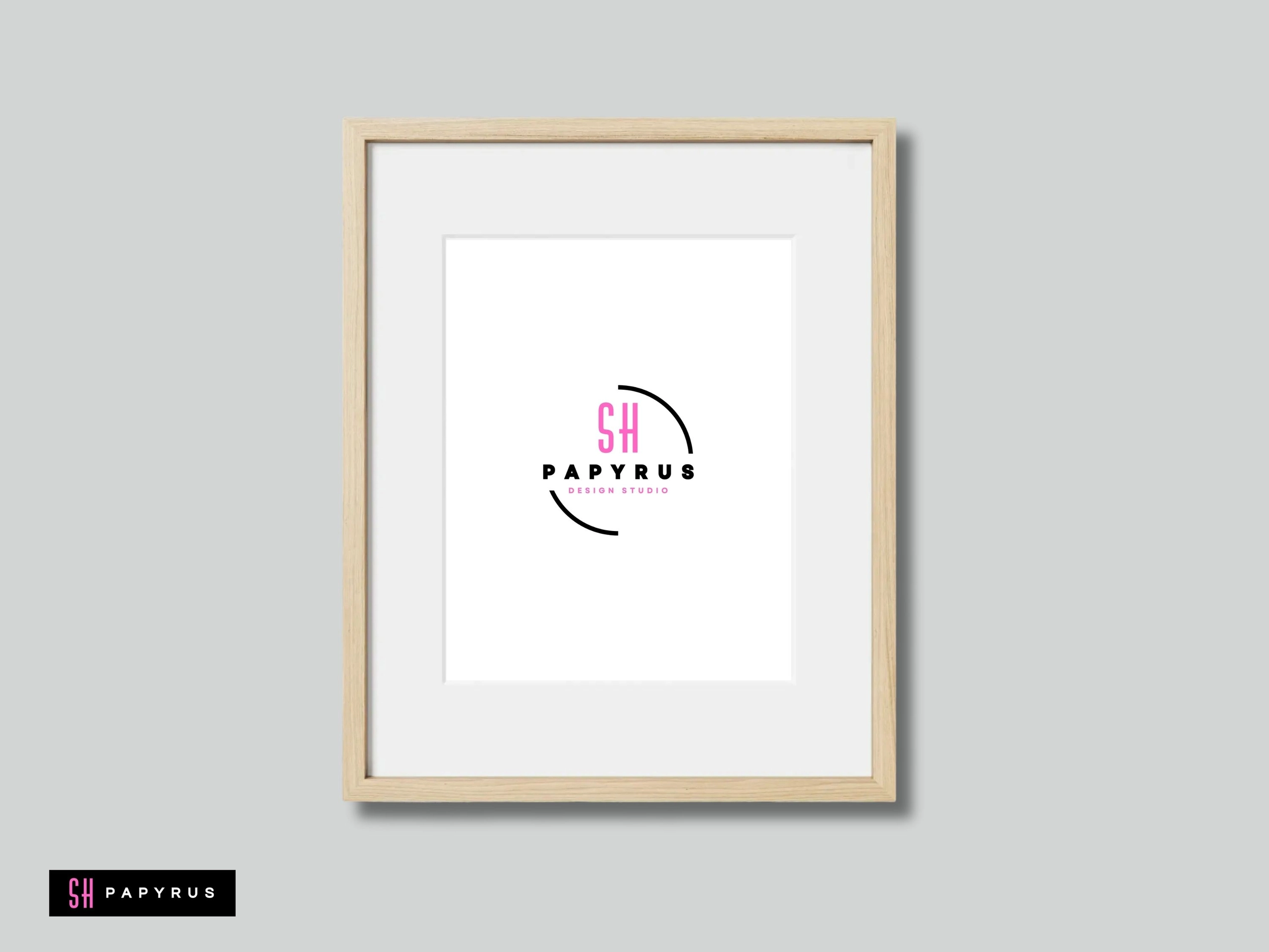 Minimalist wall art featuring a pink design studio logo in a light wood frame.